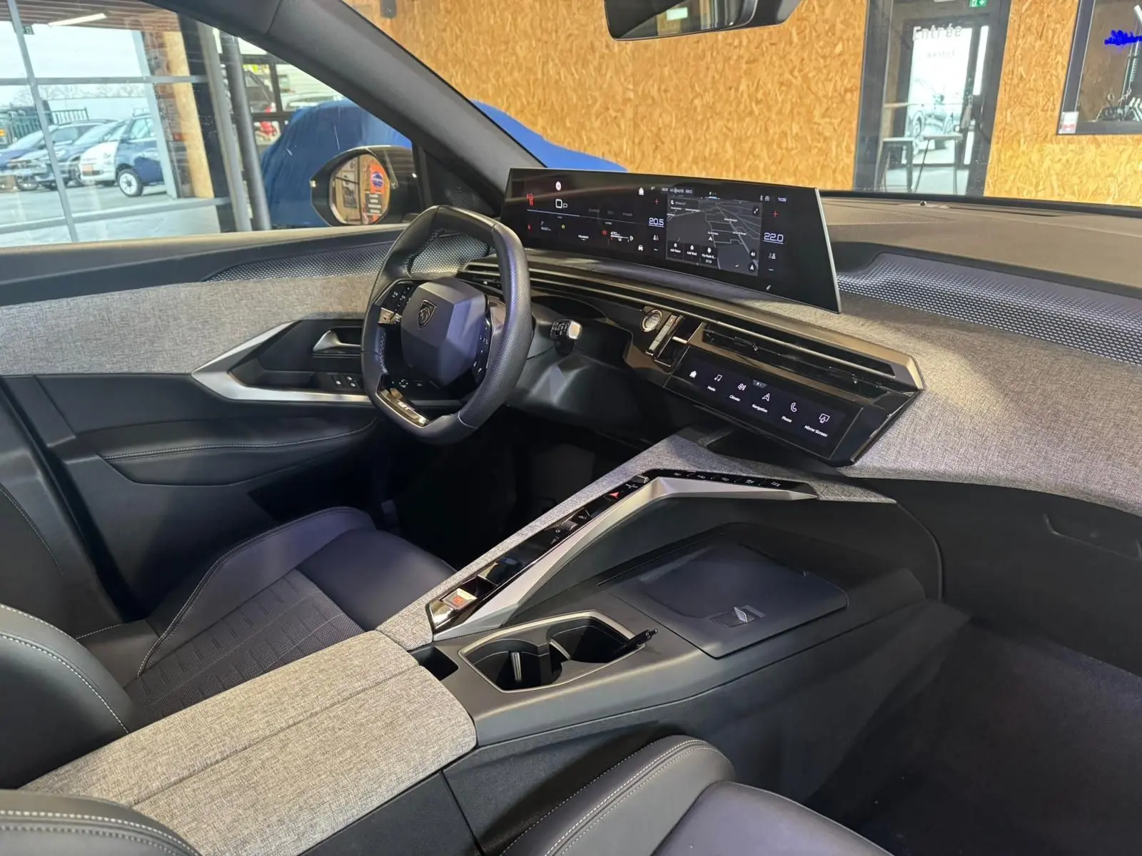 Vue intérieure côté conducteur du Peugeot 5008 1.2 Hybrid 136 GT 2025 avec tableau de bord numérique et habillage gris tissu.