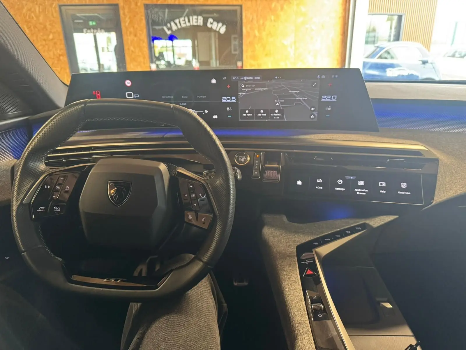 Vue intérieure du poste de conduite du Peugeot 5008 gris 2025, avec volant compact et tableau de bord numérique panoramique.