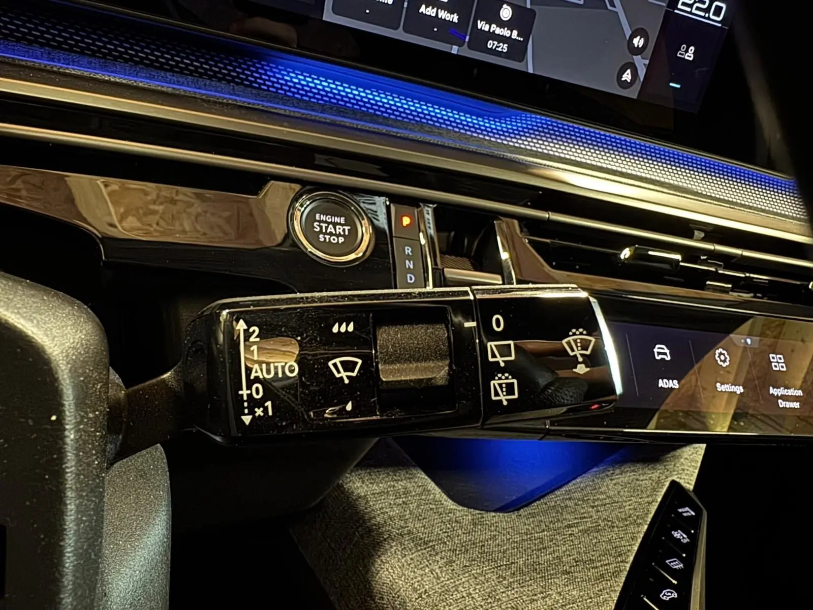 Gros plan sur la commande d’essuie-glace du tableau de bord du Peugeot 5008 gris hybride 2025, avec éclairage bleu ambiant.