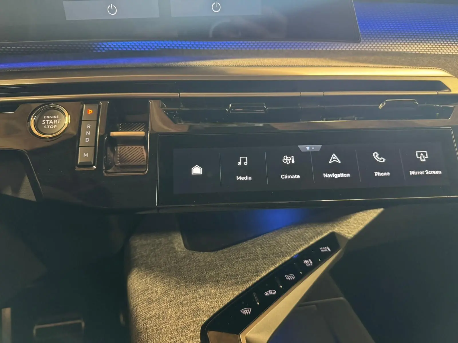 Vue rapprochée de la console centrale noire du Peugeot 5008 gris 1.2 Hybrid 136 GT, avec écran tactile et bouton start/stop.