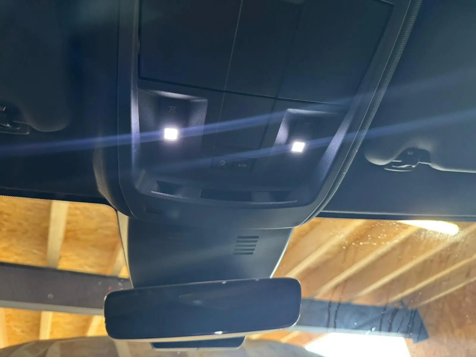 Vue intérieure en plongée sur le plafonnier et le rétroviseur d’un Peugeot 5008 gris hybride 2025.