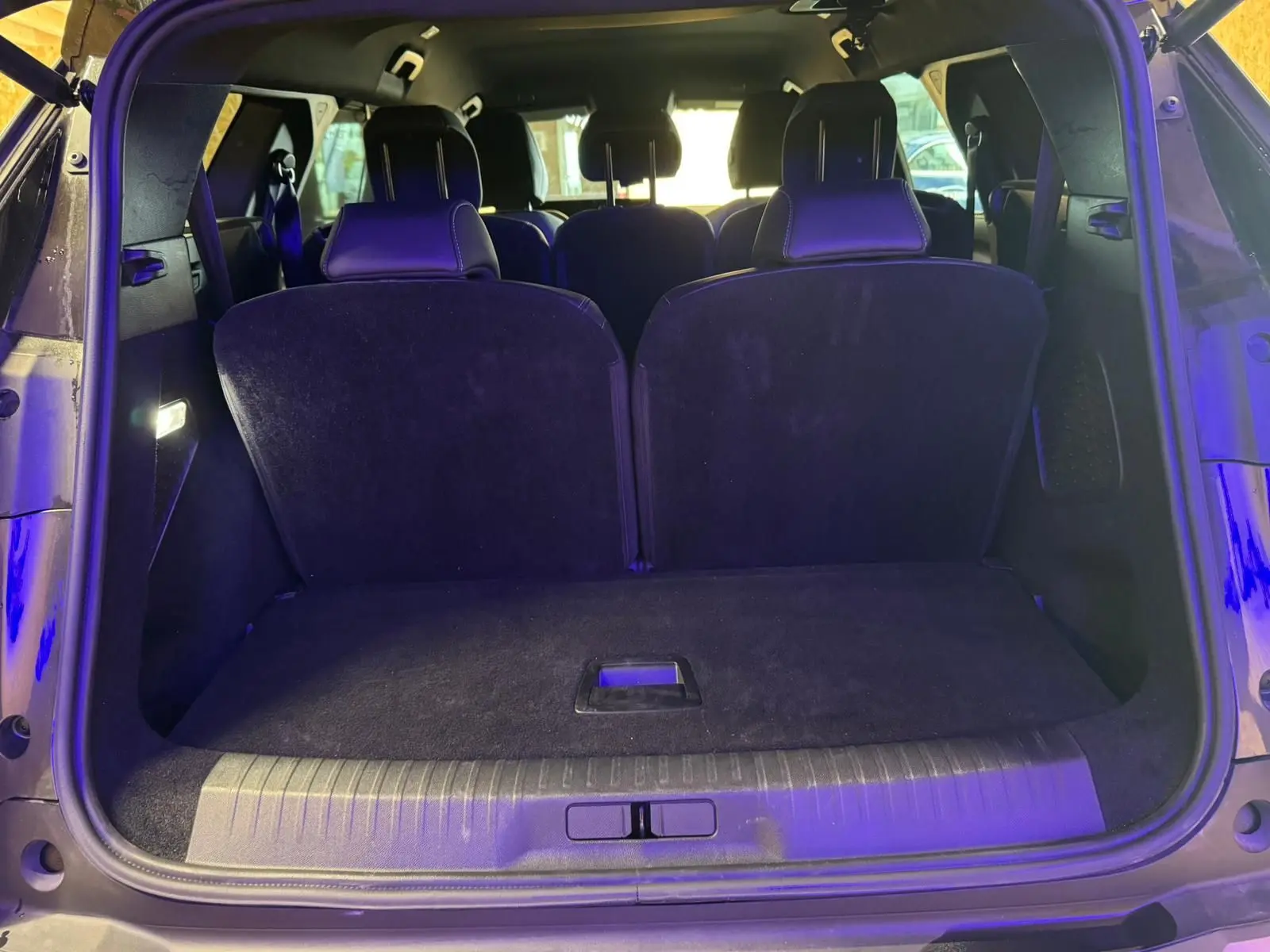 Coffre ouvert vu de l'arrière d'un Peugeot 5008 gris, montrant les sièges arrière et l'espace de chargement.