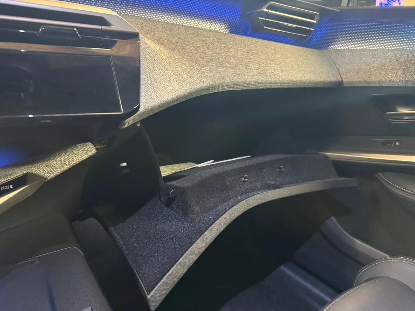 Vue intérieure côté passager du tableau de bord gris et tissu noir avec boîte à gants ouverte du Peugeot 5008 1.2 Hybrid 136 GT 2025.