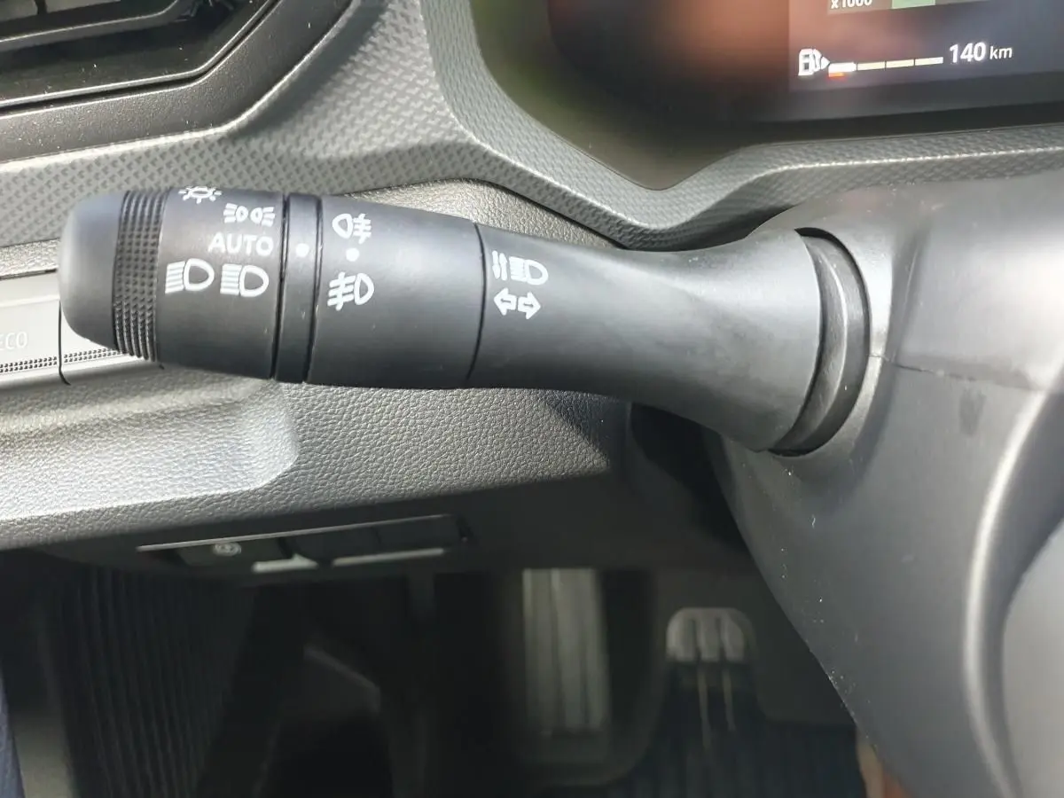 Gros plan sur la commande des feux à gauche du volant dans l'habitacle du Dacia Dokker Van gris schiste.
