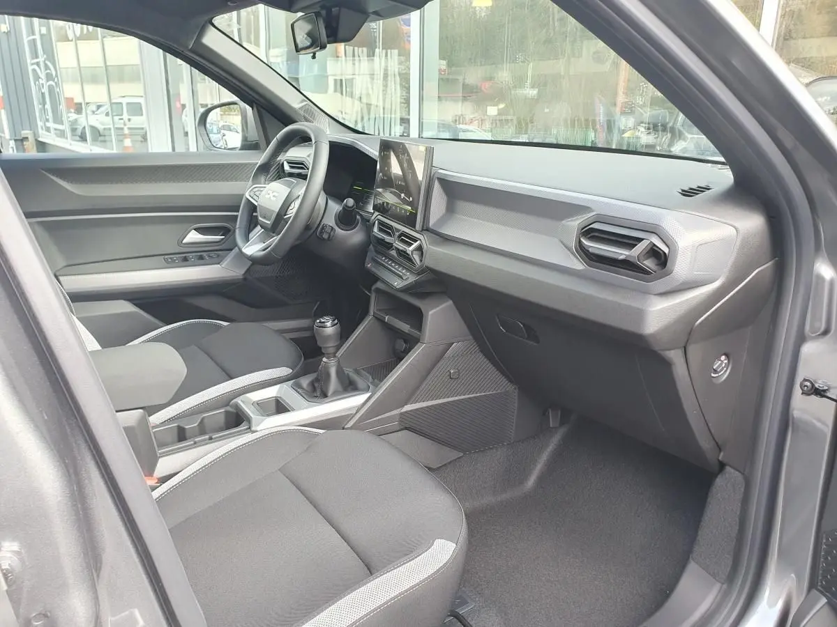 Intérieur avant droit du Dacia Dokker Van gris schiste, avec tableau de bord moderne et boîte manuelle visible.