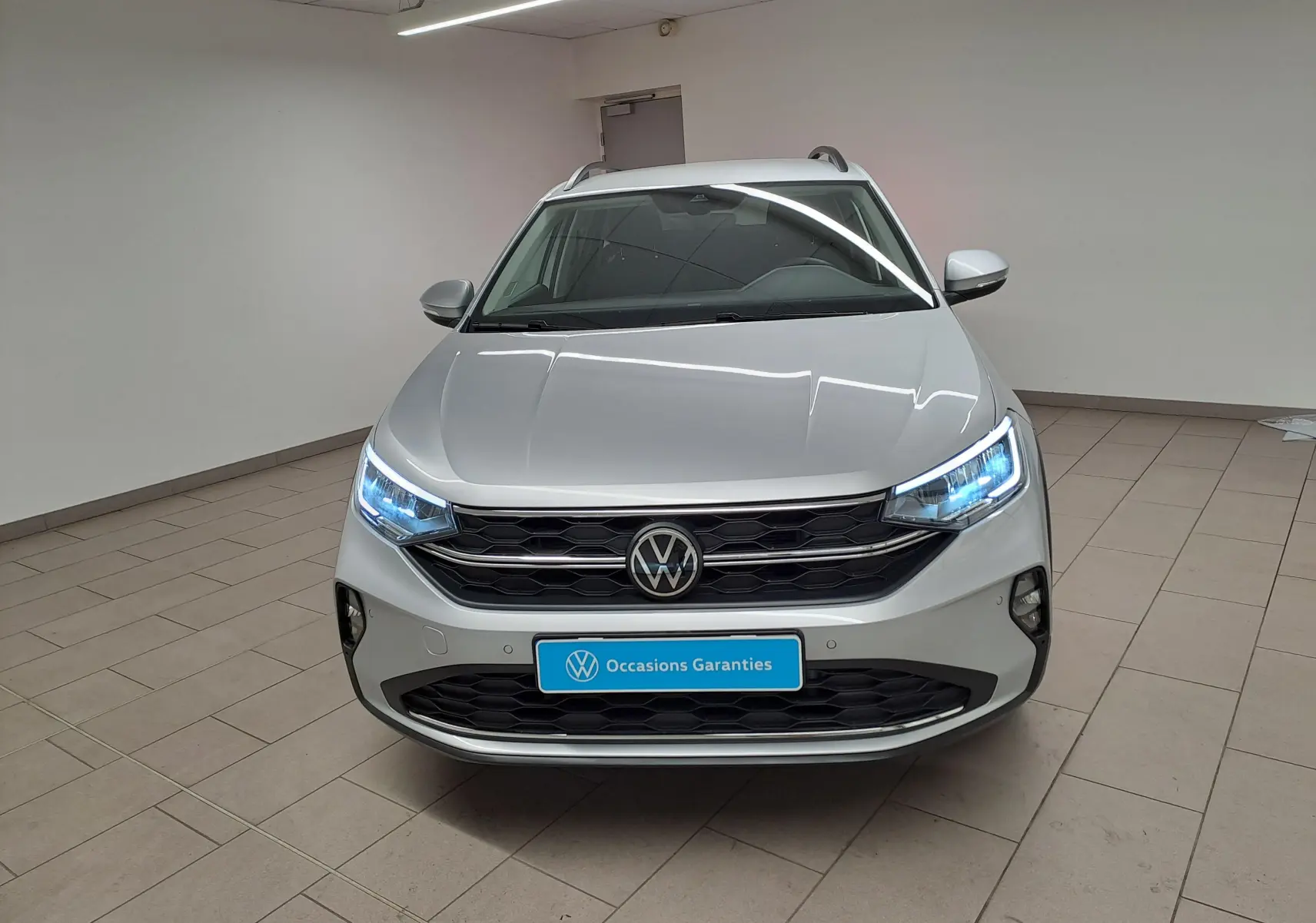 Vue avant frontale du Volkswagen Taigo 2025 en Reflet d'Argent avec phares LED allumés et calandre noire.