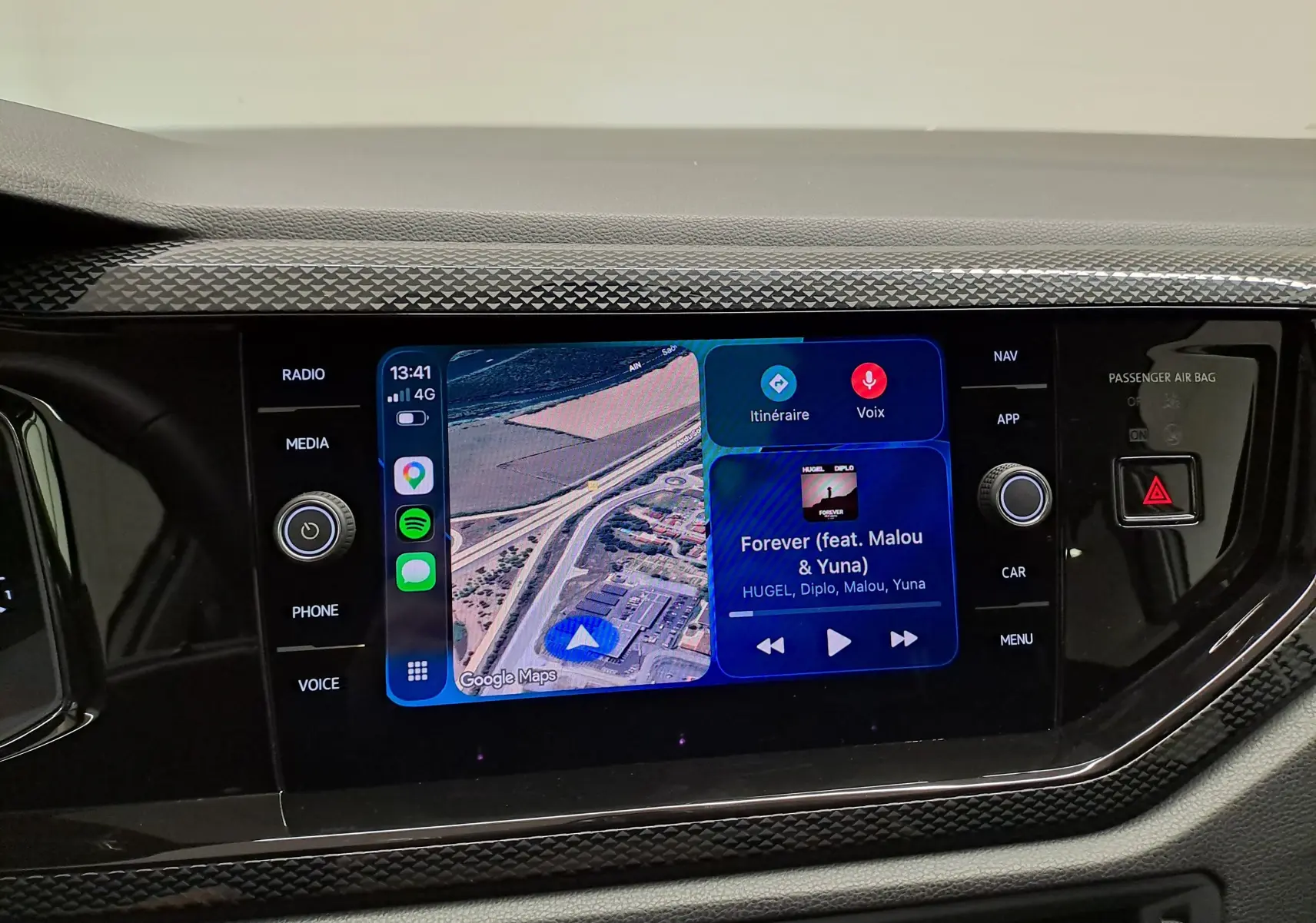 Écran tactile central du Volkswagen Taigo 2025 affichant navigation Google Maps et lecture musicale, entouré de commandes noires brillantes.