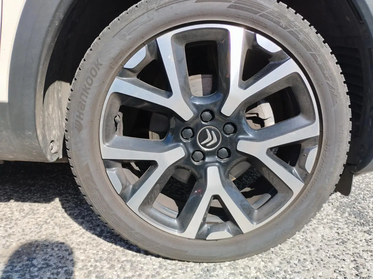 Gros plan sur la jante alliage bi-ton noir et argentée d’un Citroën C5 Aircross blanc nacré.