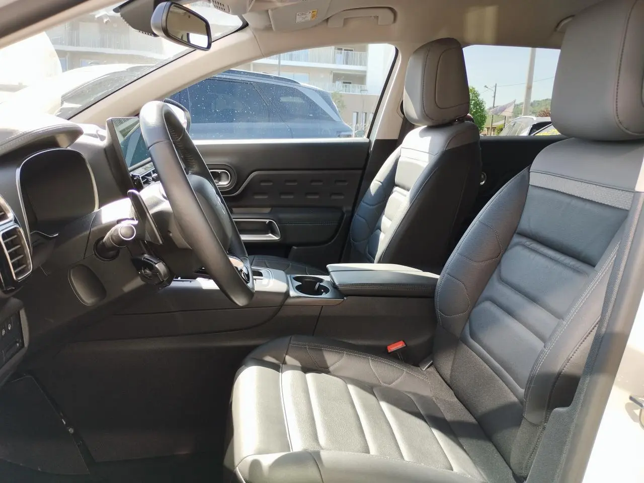 Vue intérieure côté conducteur du Citroën C5 Aircross 2022, sièges cuir noir et console centrale avec accoudoir.
