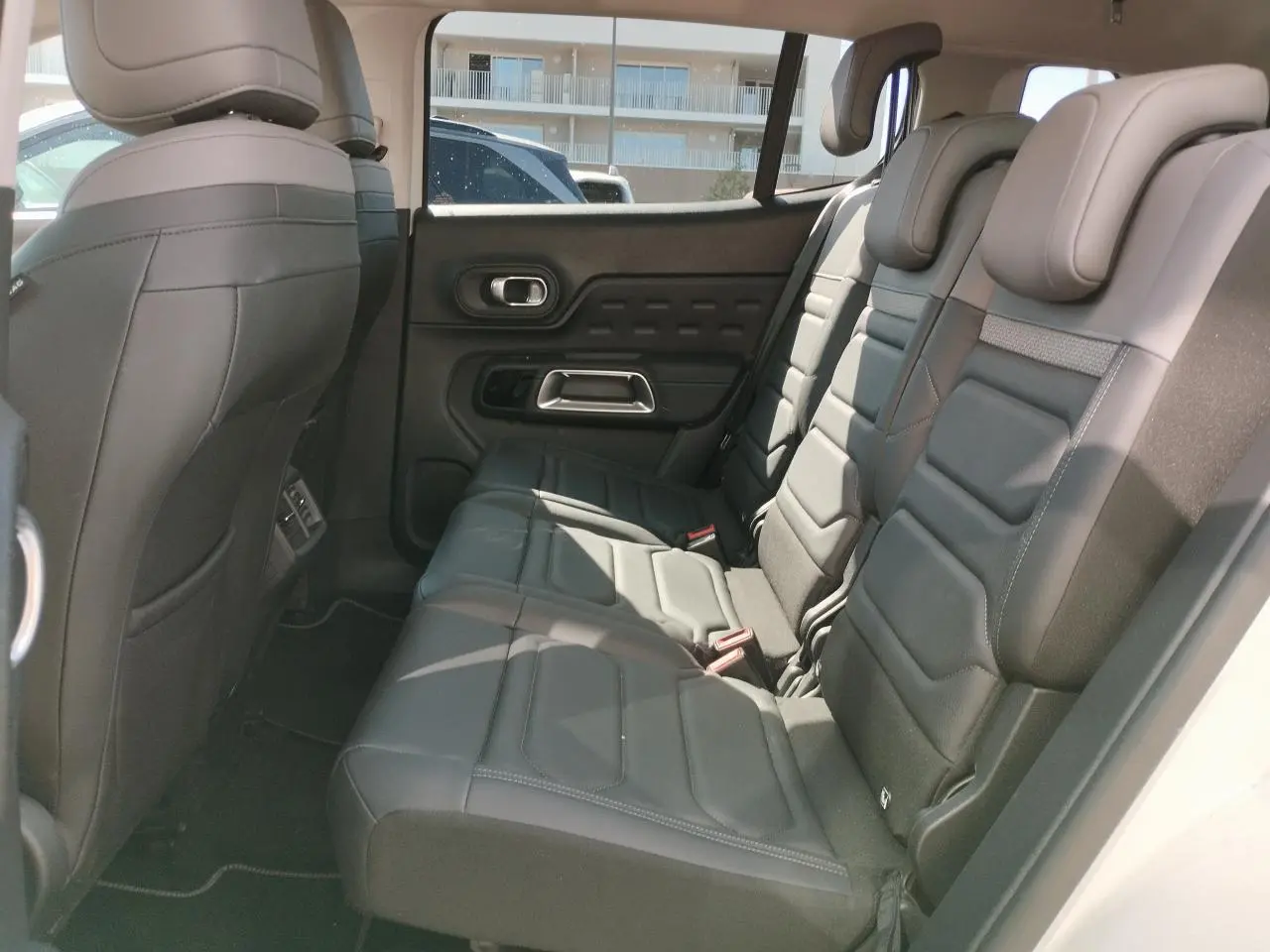 Vue latérale droite de l'habitacle arrière du Citroën C5 Aircross 2022 avec sièges cuir noir et appuie-têtes intégrés.