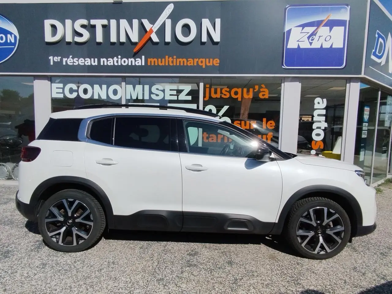 Profil côté gauche d'un Citroën C5 Aircross blanc nacré avec toit noir et jantes alliage bi-ton 19 pouces.