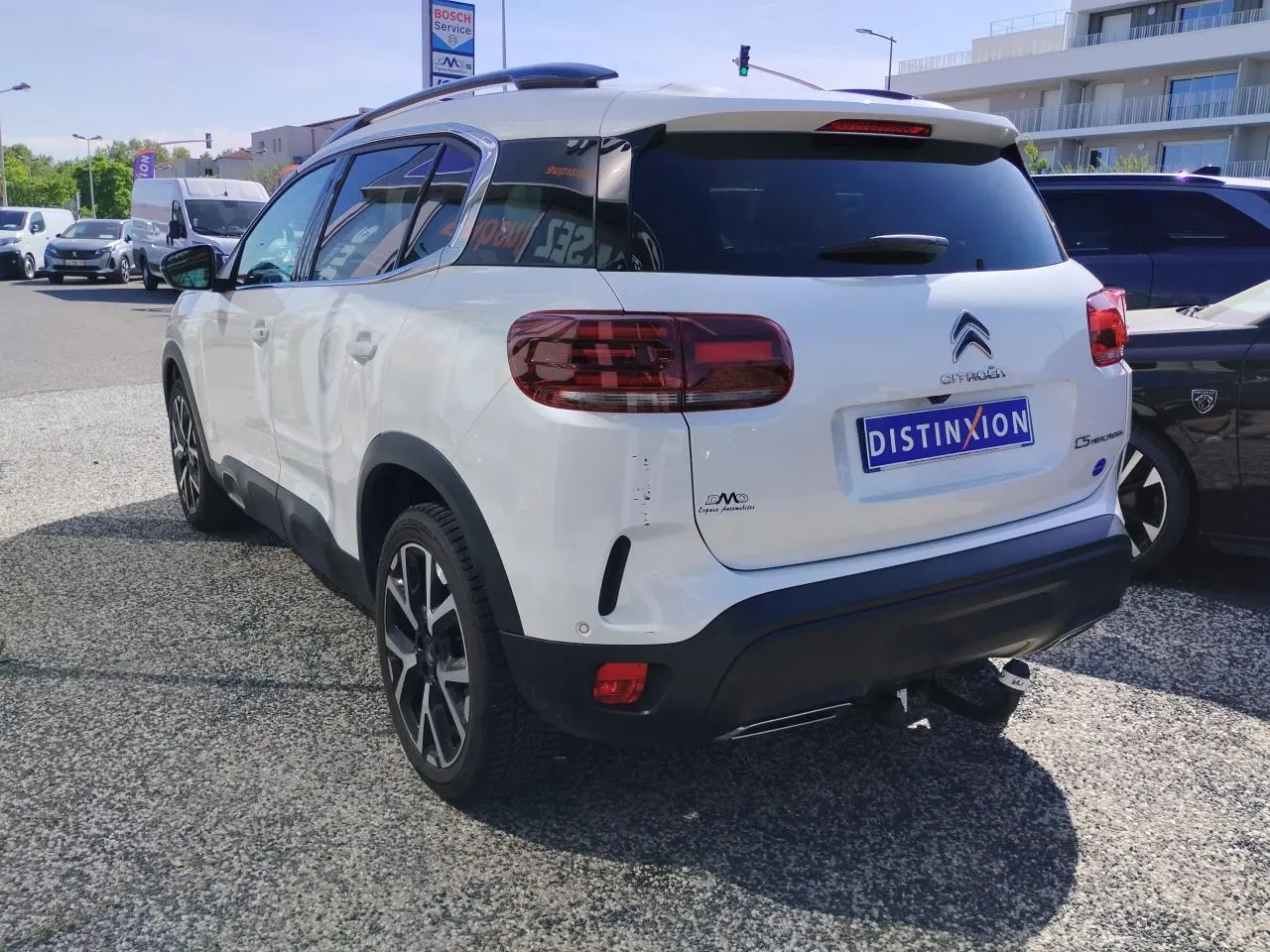 Vue 3/4 arrière droite d'un Citroën C5 Aircross blanc nacré avec toit noir et attelage col de cygne.