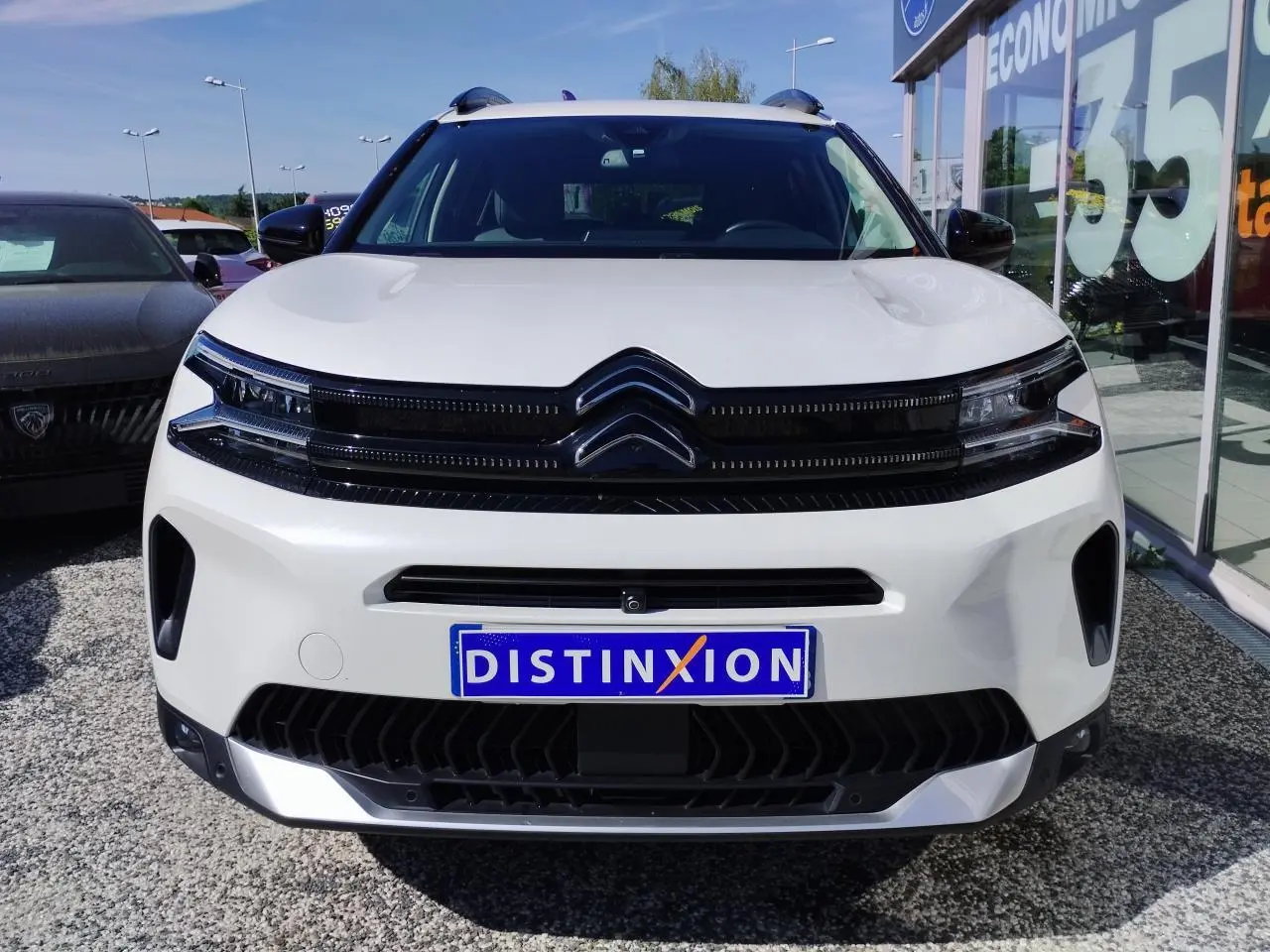 Vue avant d'un Citroën C5 Aircross blanc nacré avec calandre noire brillante et logo double chevron.