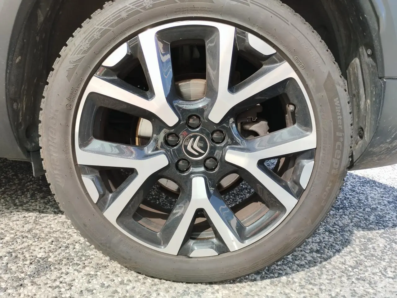 Gros plan sur la jante alliage bi-ton noir et argentée avec logo Citroën au centre du C5 Aircross blanc nacré.