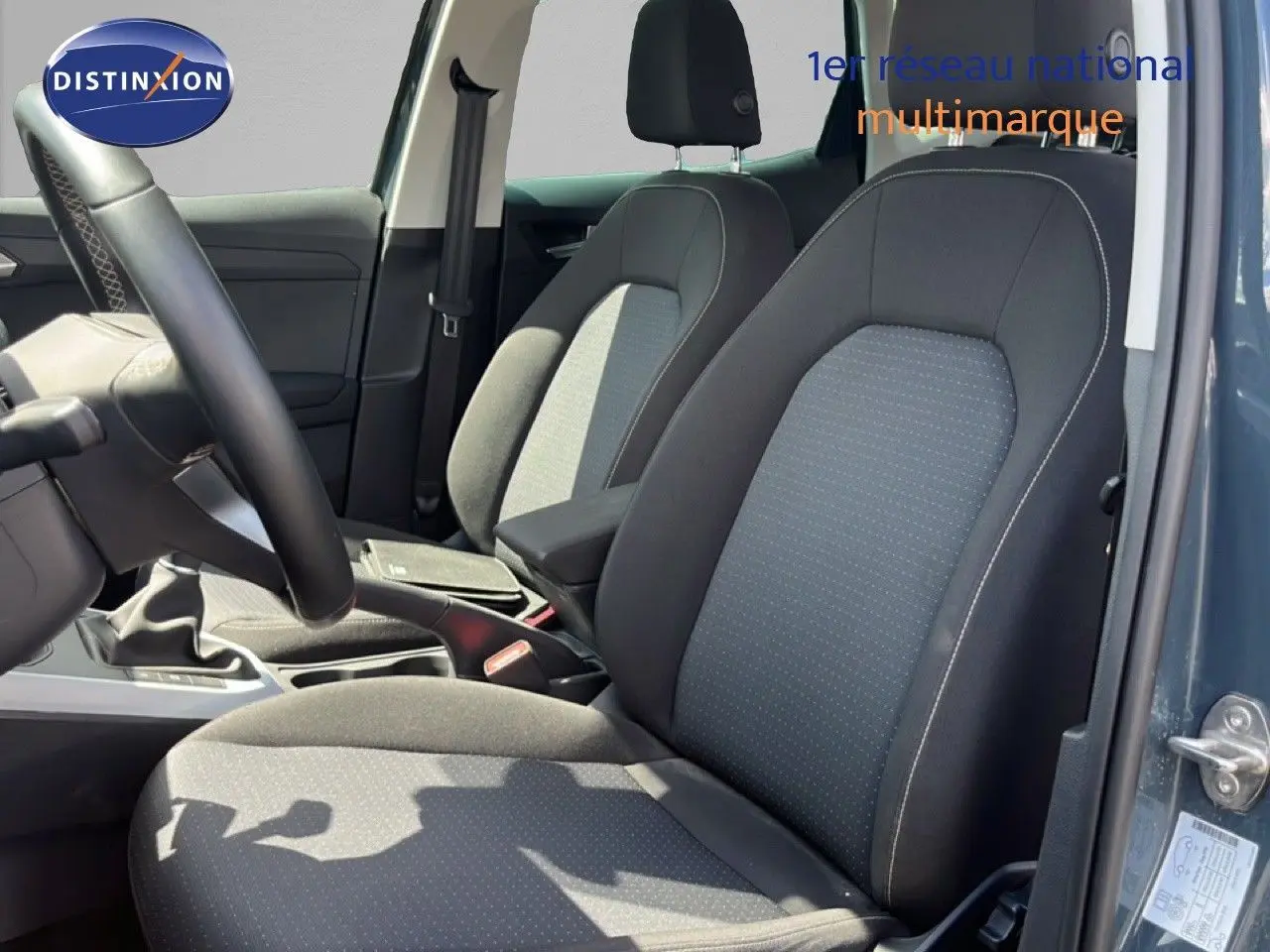 Vue intérieure côté gauche montrant les sièges avant en tissu gris noir d'une SEAT Arona Bleu Fjord 2025.