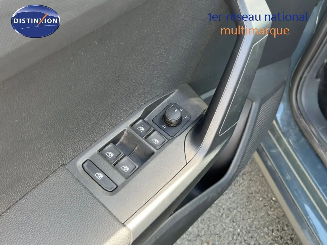 Gros plan sur les commandes des vitres et rétroviseurs côté conducteur d'un SEAT Arona bleu Fjord avec toit blanc.