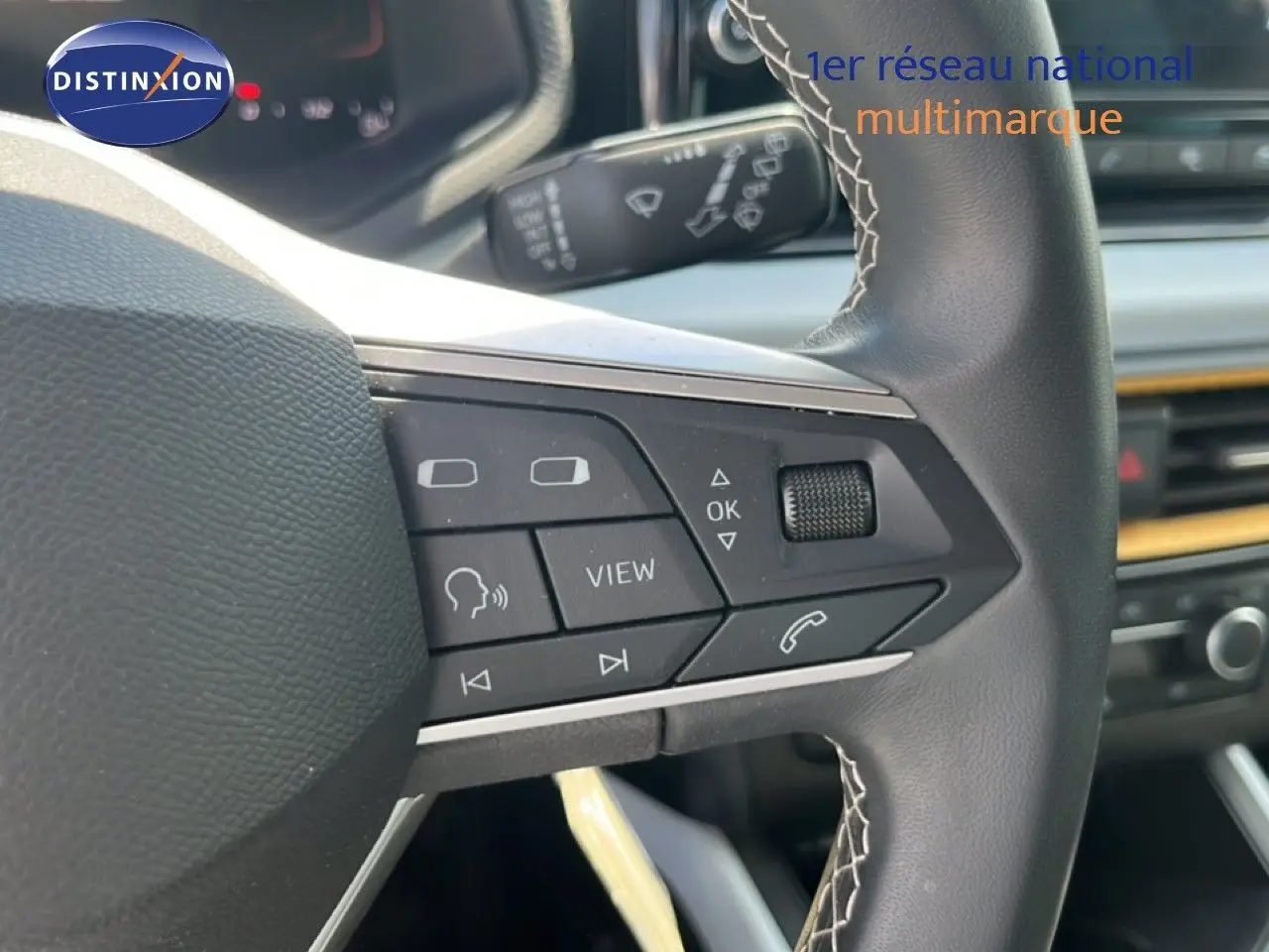 Gros plan sur le volant multifonction en cuir noir avec surpiqûres blanches du SEAT Arona 2025, intérieur gris-noir.