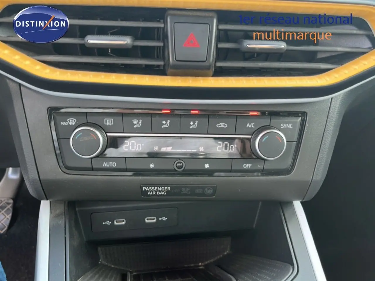 Gros plan sur la console centrale du SEAT Arona bleu Fjord, avec climatisation digitale et bordure jaune contrastante.