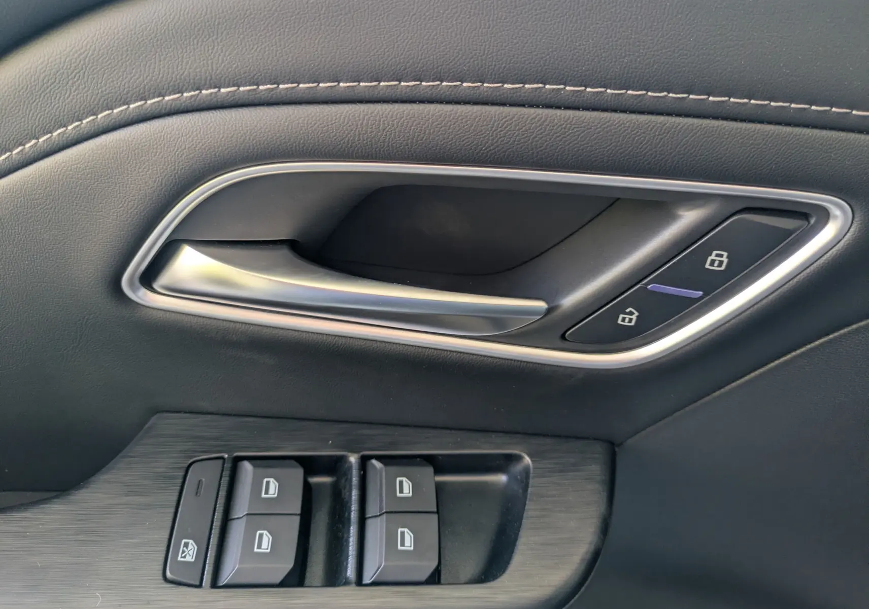 Vue intérieure côté gauche des sièges arrière en similicuir noir perforé du MG MOTOR ZS 1.5 L Hybrid+ 2026 avec porte ouverte.