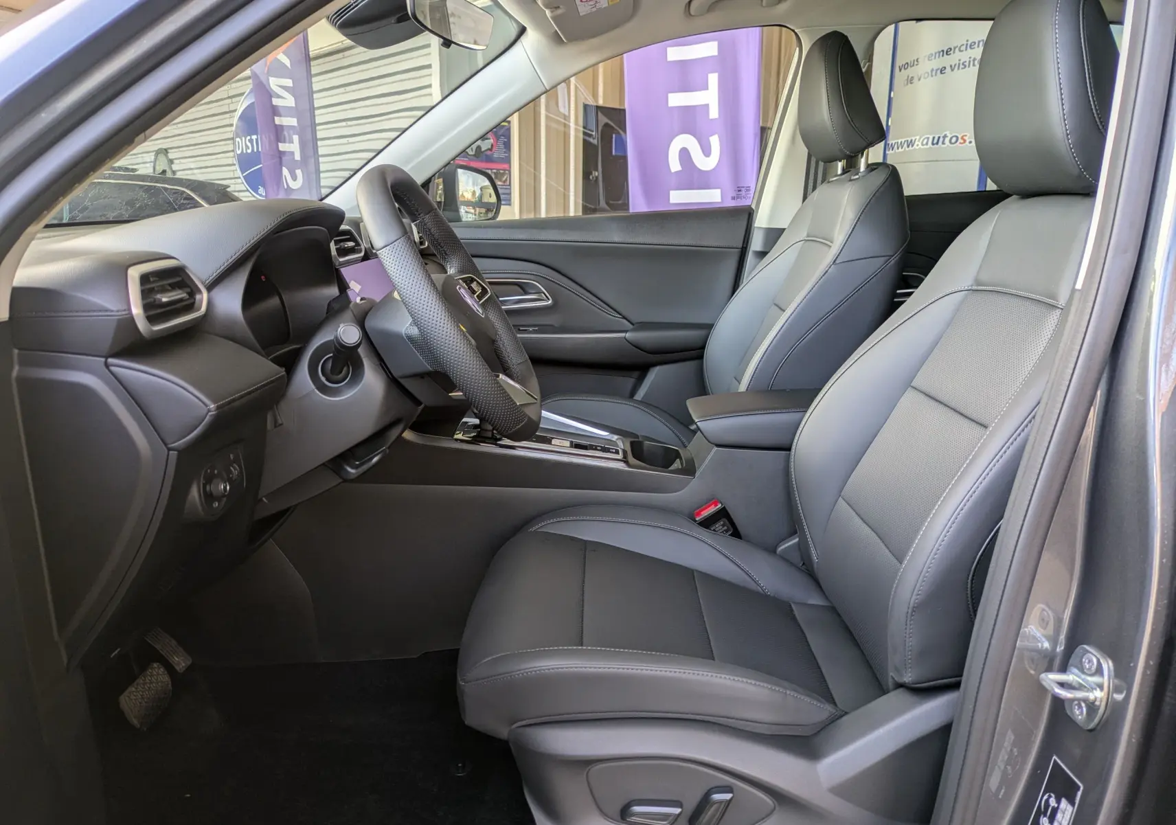 Vue intérieure centrée sur le volant en cuir perforé et la console avec écran tactile éteint du MG Motor ZS 2026 Candem Grey.