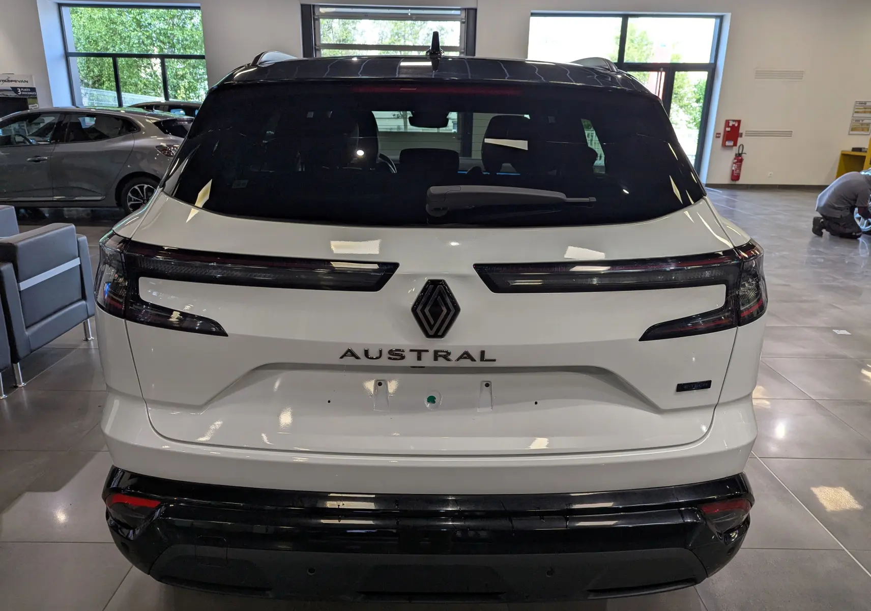 Vue arrière d'un Renault Austral blanc nacré avec toit noir, mettant en valeur ses feux arrière horizontaux et son logo central.