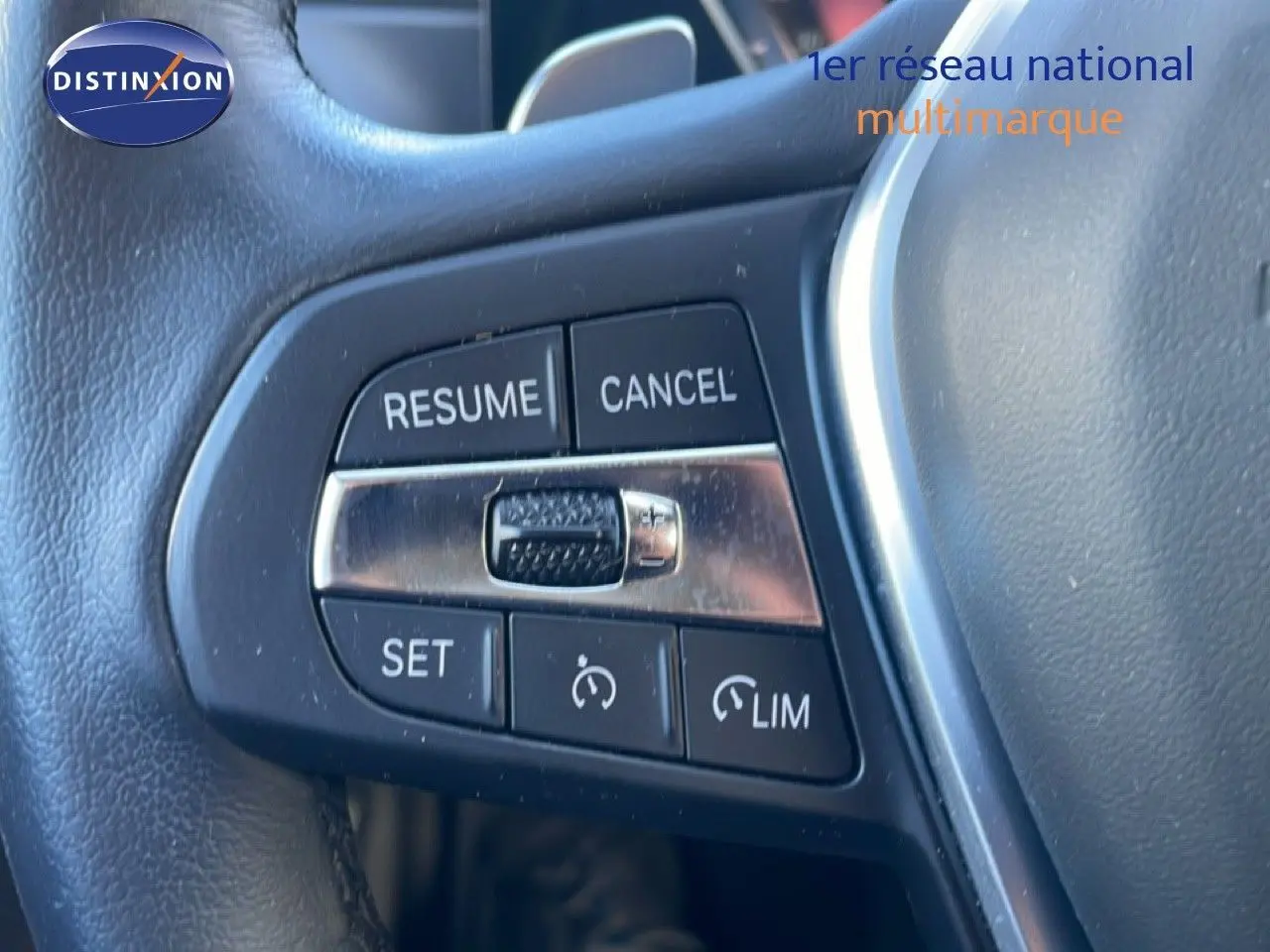 Gros plan sur les commandes de régulateur de vitesse au volant noir d’une BMW Série 3 Touring F31 316d 2022.