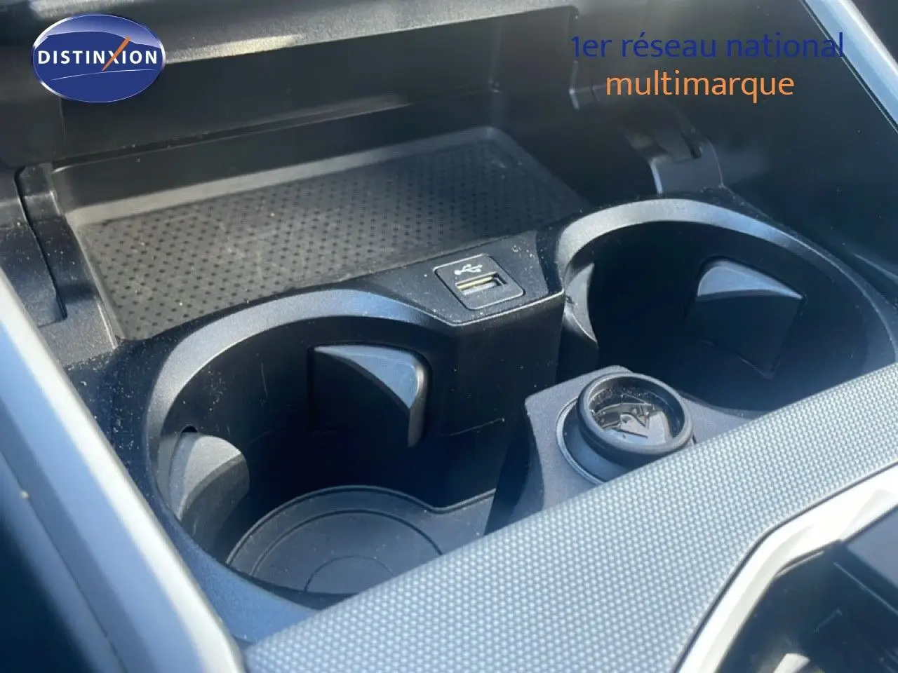 Gros plan sur les porte-gobelets et prise USB du compartiment central d’une BMW Série 3 Touring noire.