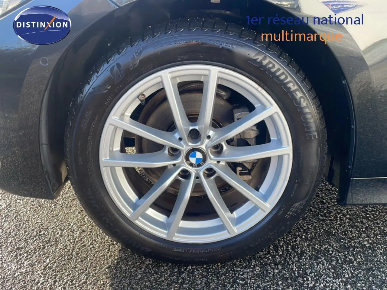 Gros plan sur la roue avant gauche d’une BMW Série 3 Touring F31 noire, avec jante alliage argent et pneu Bridgestone.