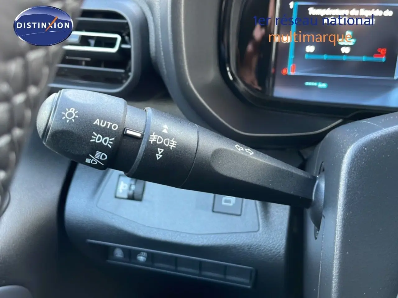 Gros plan sur la manette de commandes d'éclairage à gauche du volant dans l'habitacle du Citroën Berlingo blanc glacier.