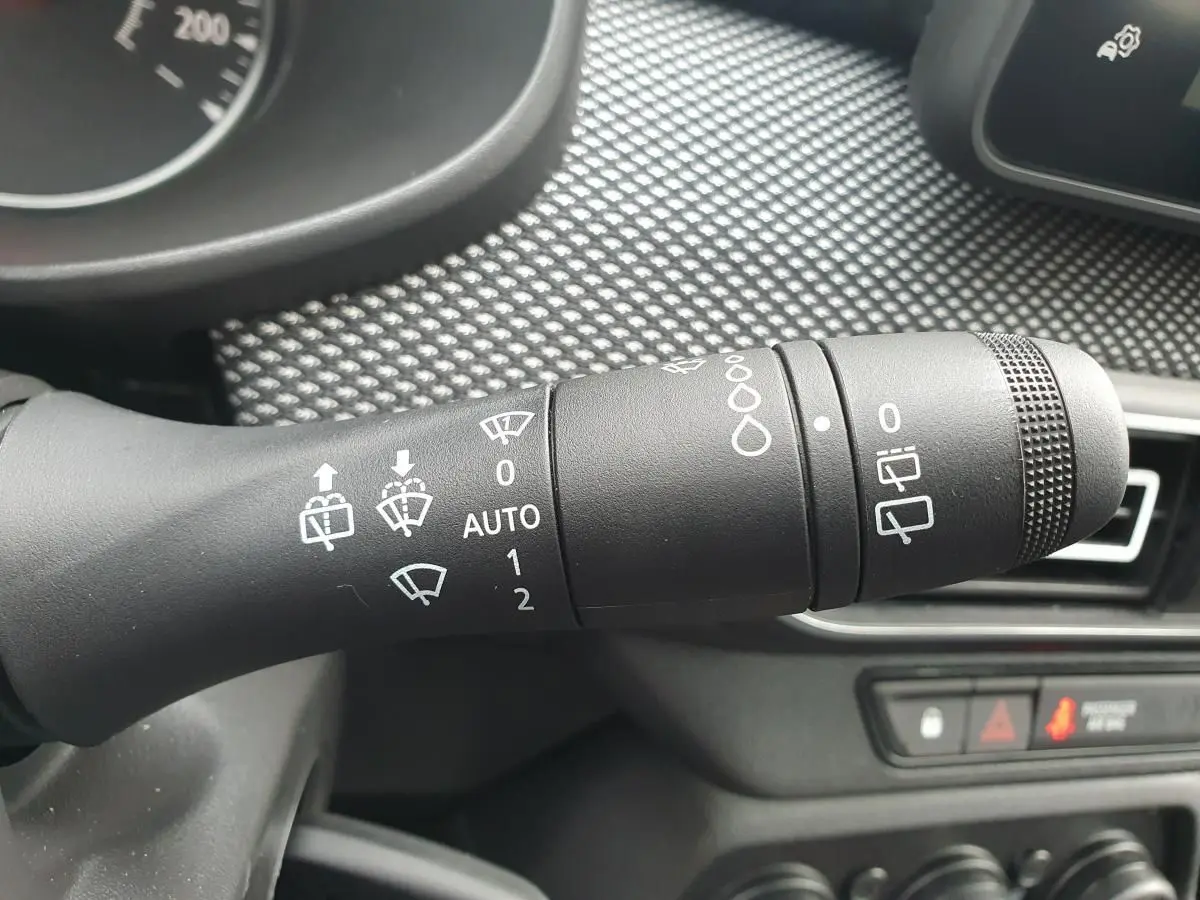 Gros plan sur la commande des essuie-glaces du DACIA Sandero 2025, intérieur noir avec tableau de bord texturé.