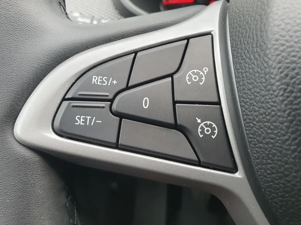Gros plan sur les commandes du régulateur de vitesse au volant d’une Dacia Sandero 2025, intérieur noir.