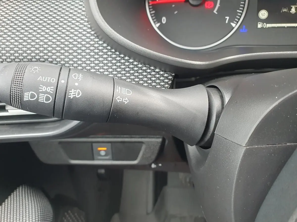 Gros plan sur la commande des feux et clignotants dans l’habitacle noir du Dacia Sandero 2025.
