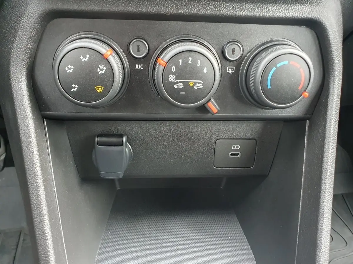 Gros plan sur les commandes de climatisation manuelle et prise USB du tableau de bord d'une Dacia Sandero 2025.