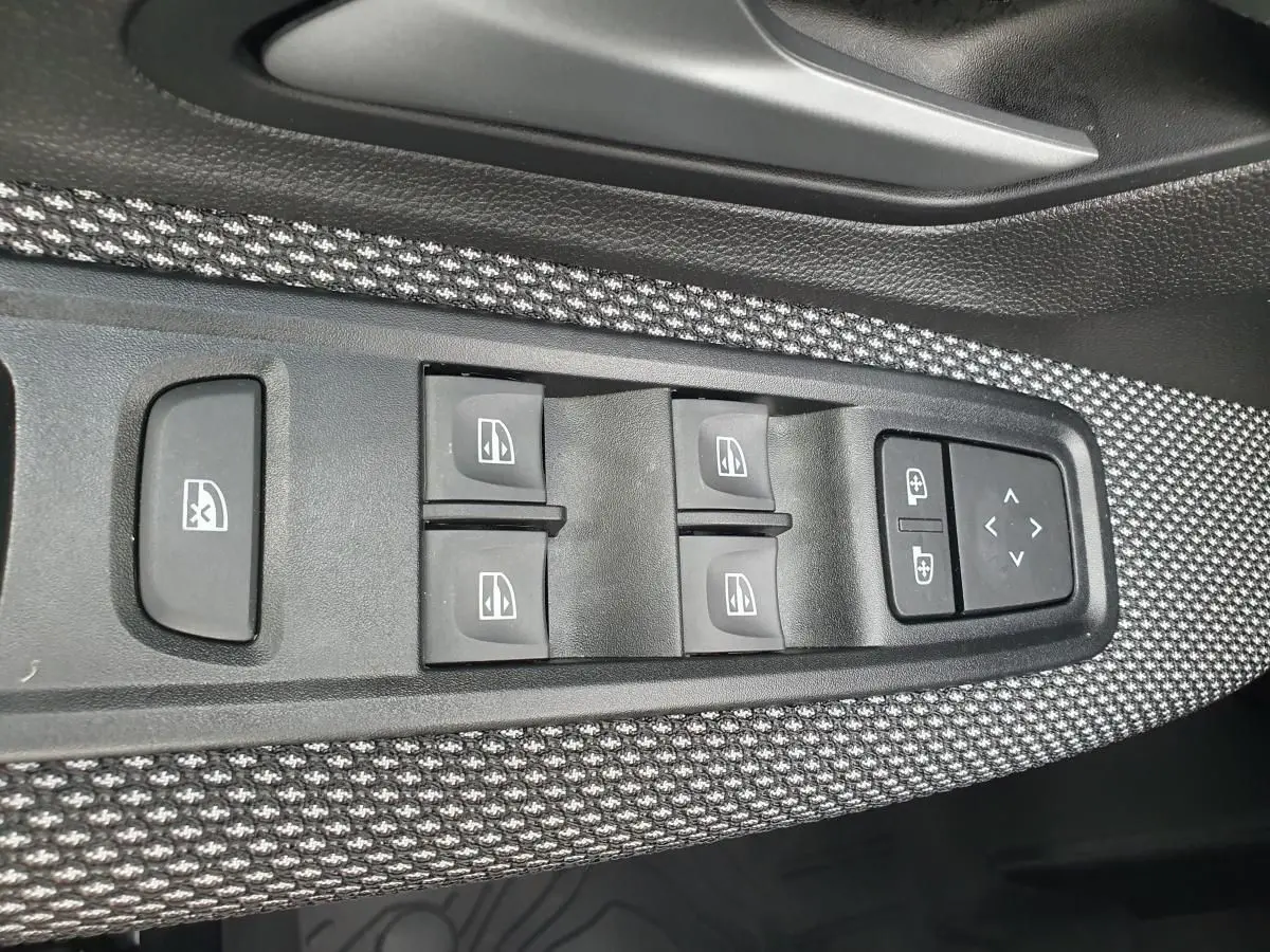 Panneau de commandes des vitres électriques et réglages des rétroviseurs sur la porte côté conducteur d’une Dacia Sandero.