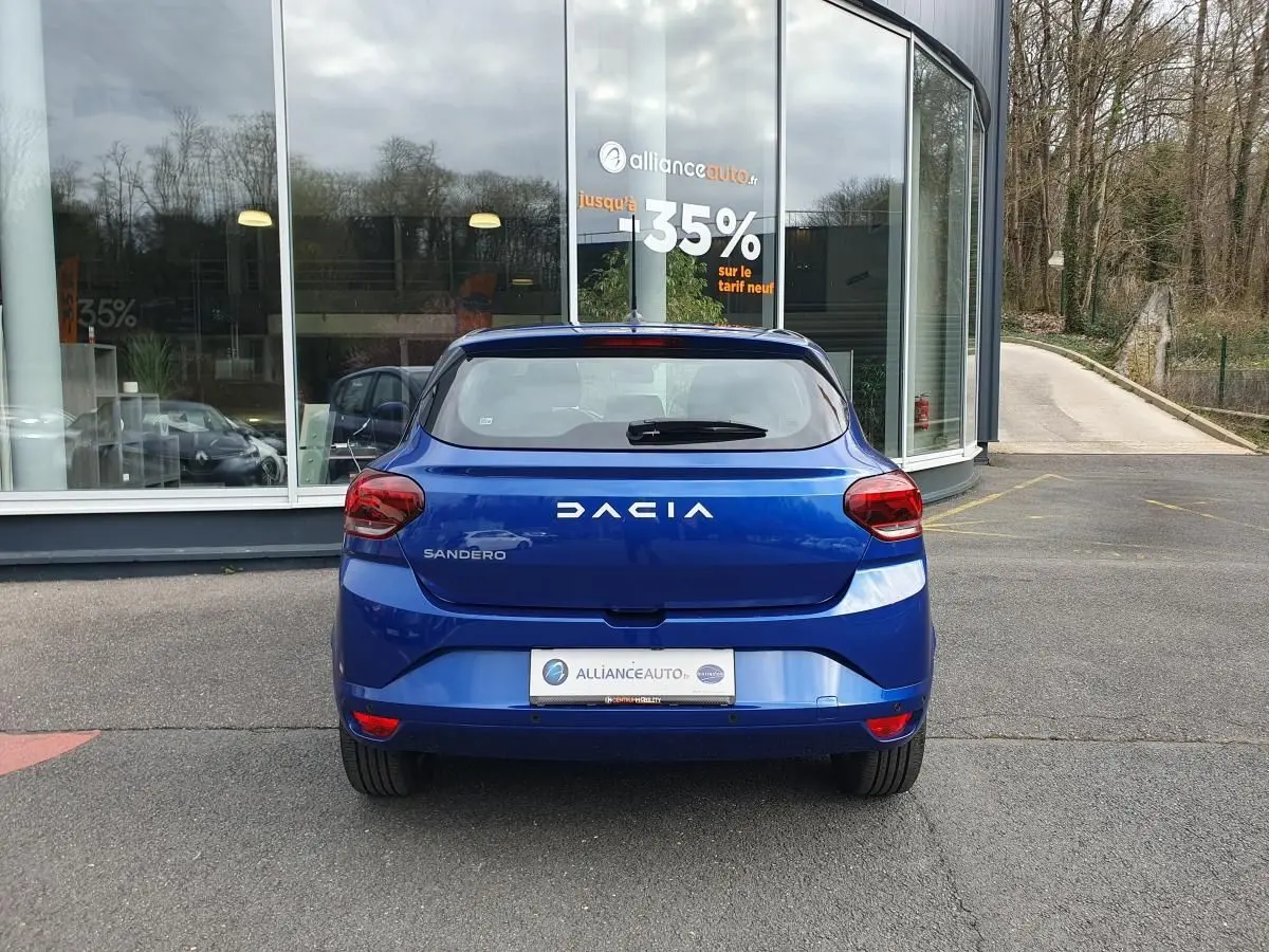 Vue arrière d'une Dacia Sandero 2025 bleu Iron, avec feux arrière rouges et logo DACIA bien visible.