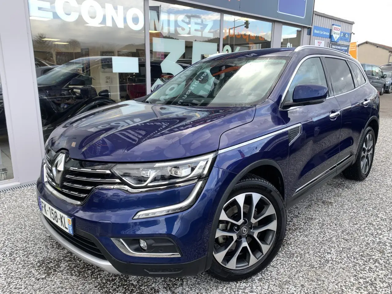Renault Koleos bleu foncé en 3/4 avant droit, avec jantes alliage 19 pouces et signature lumineuse LED.