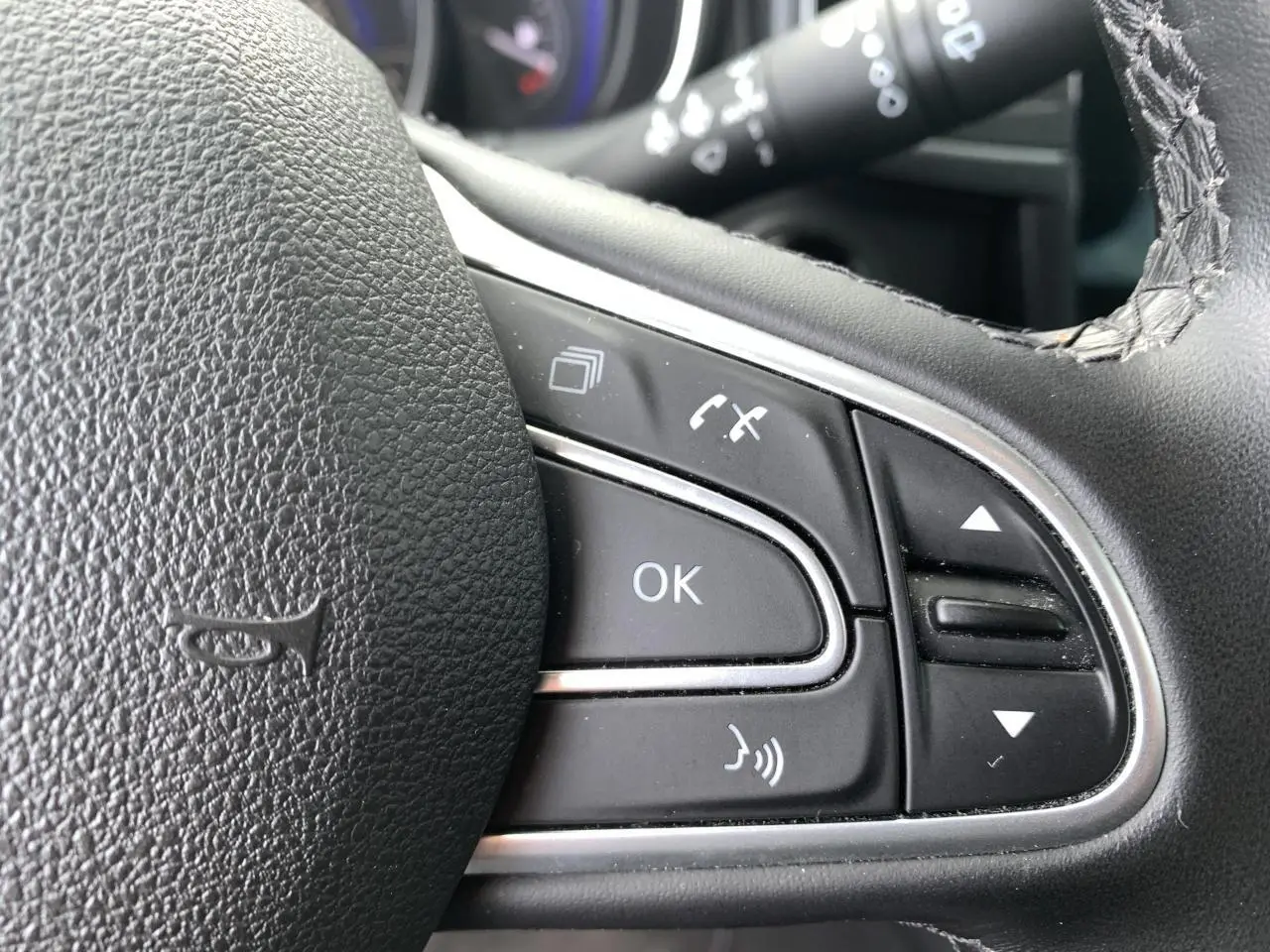 Gros plan sur les commandes multifonctions noires du volant cuir du Renault Koleos 2019.