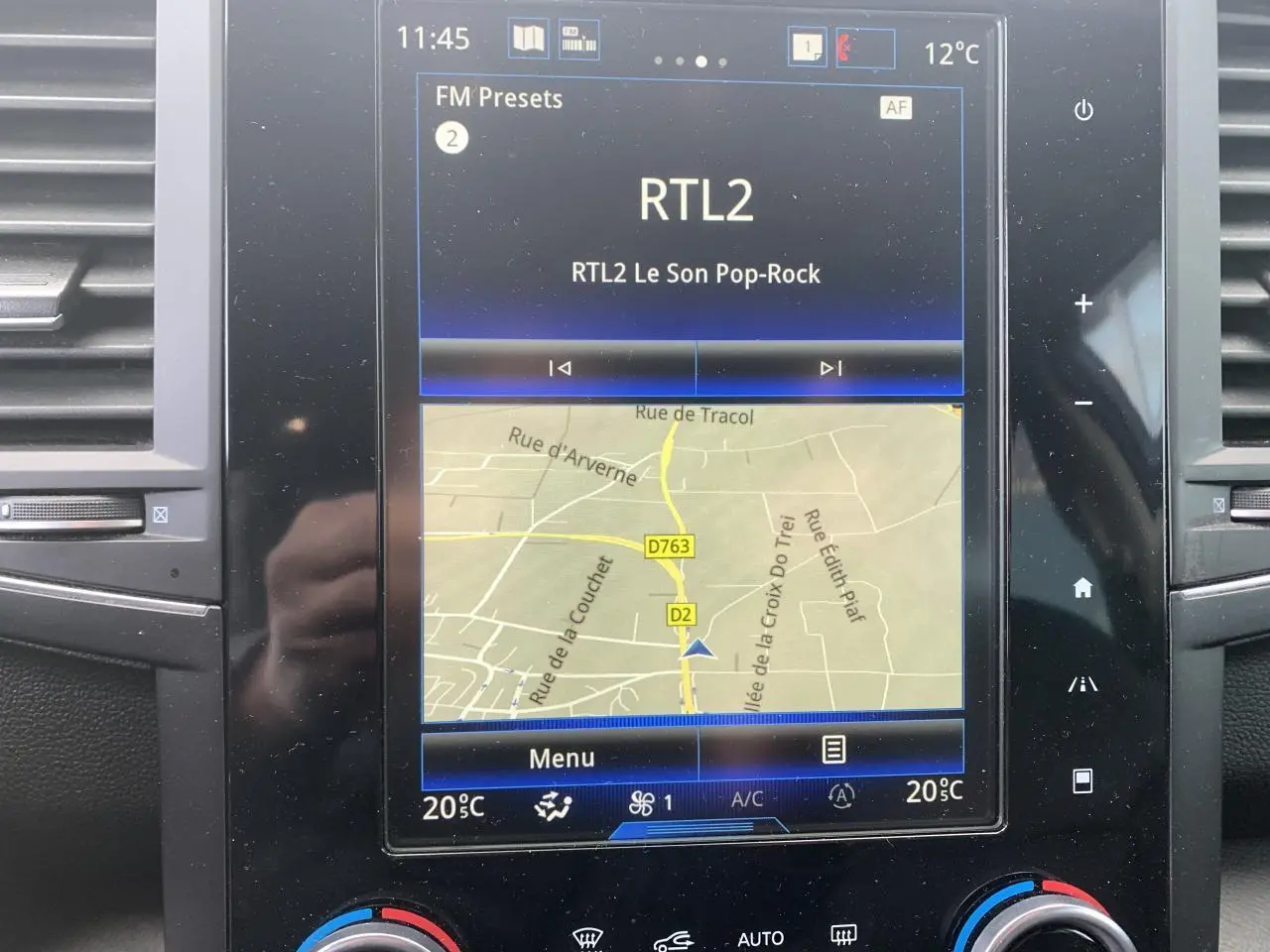 Écran tactile central du Renault Koleos 2019 affichant la navigation et la radio, avec commandes climatisation visibles.