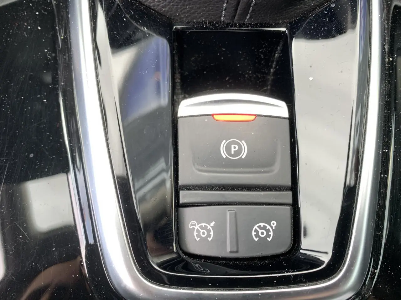 Gros plan sur la console centrale noire brillante du Renault Koleos 2019 avec boutons de frein à main et régulateur de vitesse.