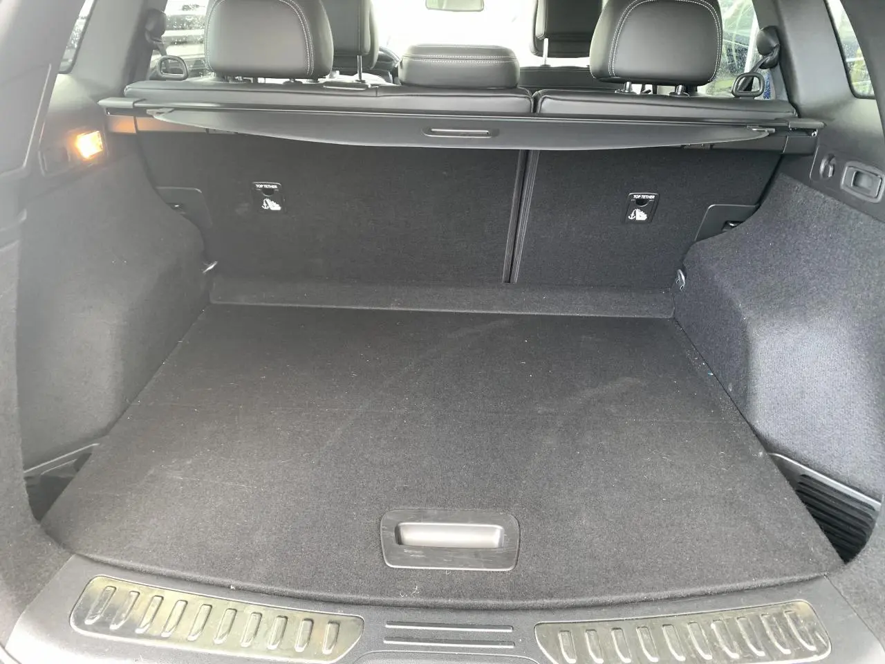 Coffre ouvert vu de l'arrière d'un Renault Koleos 2019 bleu foncé avec banquette arrière et cache-bagages noirs.