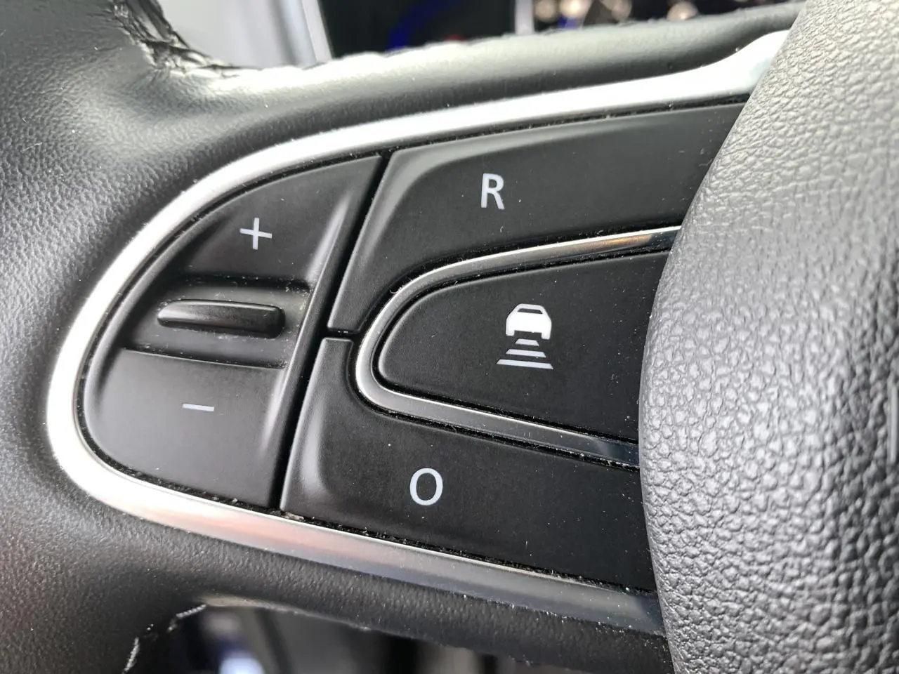 Gros plan sur les commandes noires du volant cuir du Renault Koleos 2019, version Intens, avec contour chromé.