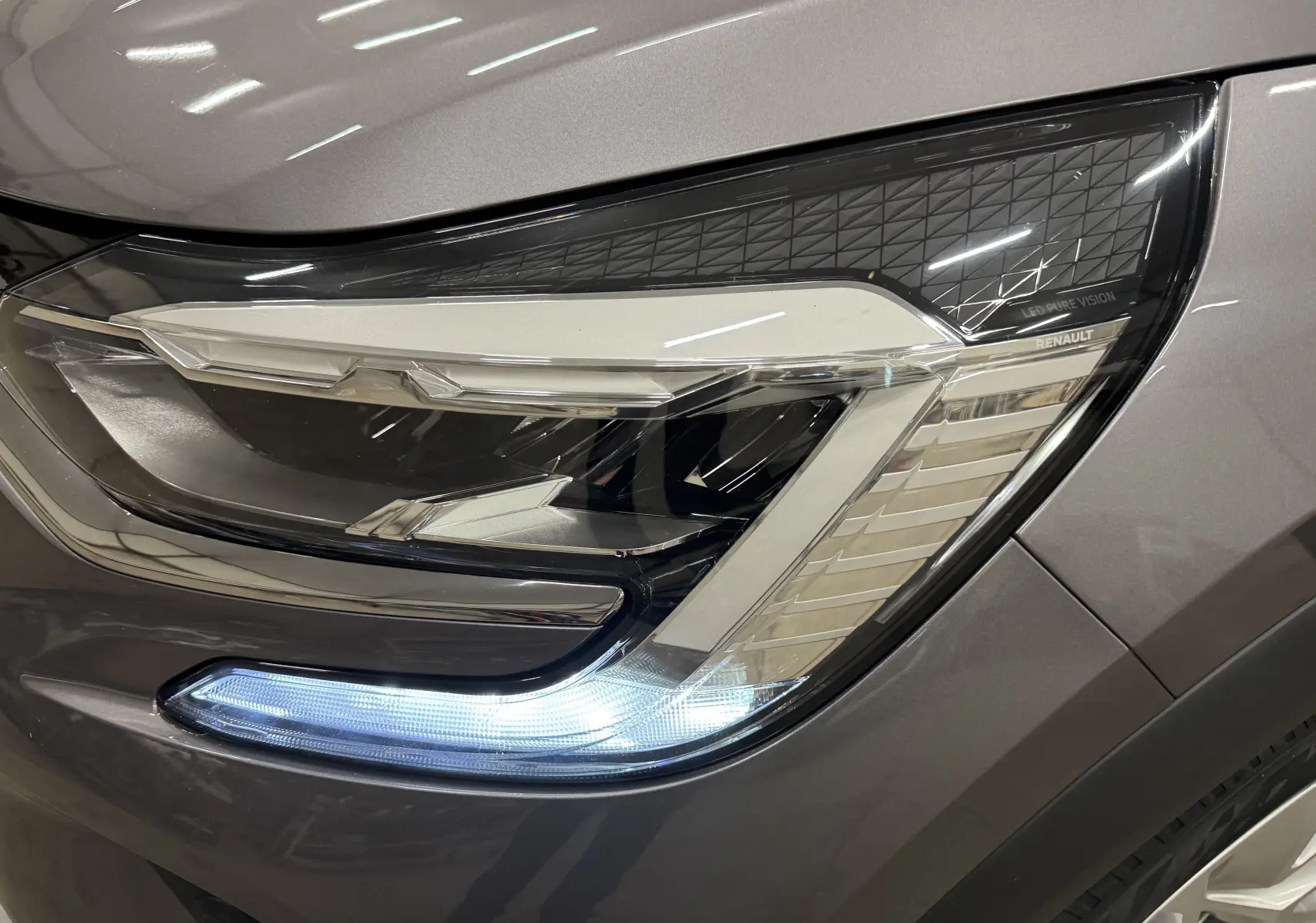 Gros plan sur le phare avant droit LED d’un Renault Captur gris foncé avec toit noir, version TCE 90 CH BUSINESS 2021.
