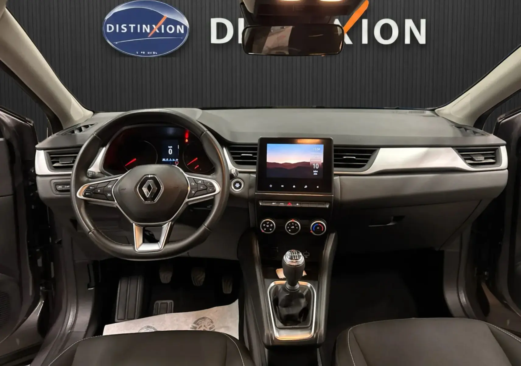Vue intérieure frontale du tableau de bord et volant du Renault Captur TCE 90 Business, avec écran tactile et levier de vitesse manuel.