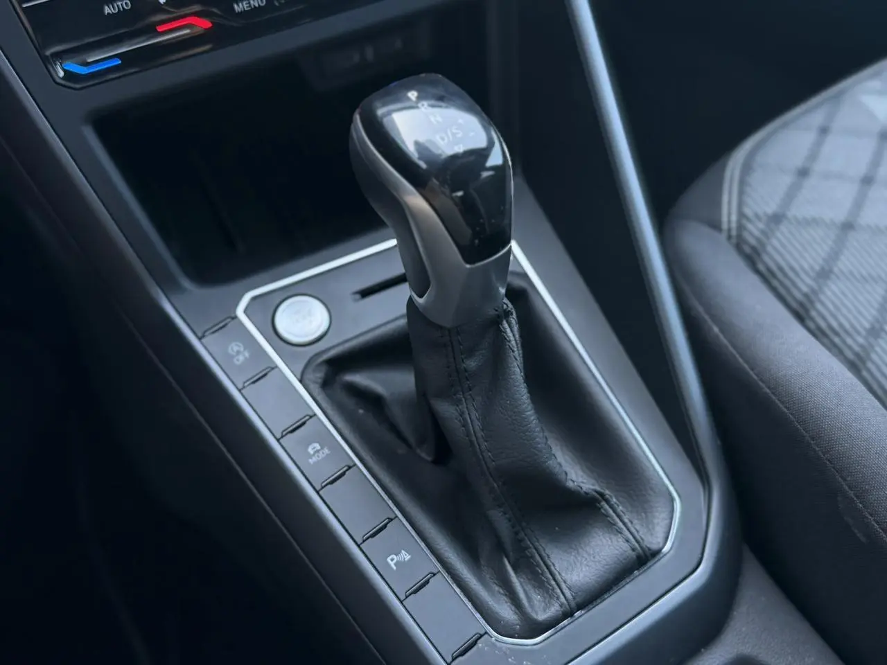 Gros plan sur la console centrale du Volkswagen Taigo gris intense, mettant en valeur le levier de vitesse automatique et les commandes adjacentes.