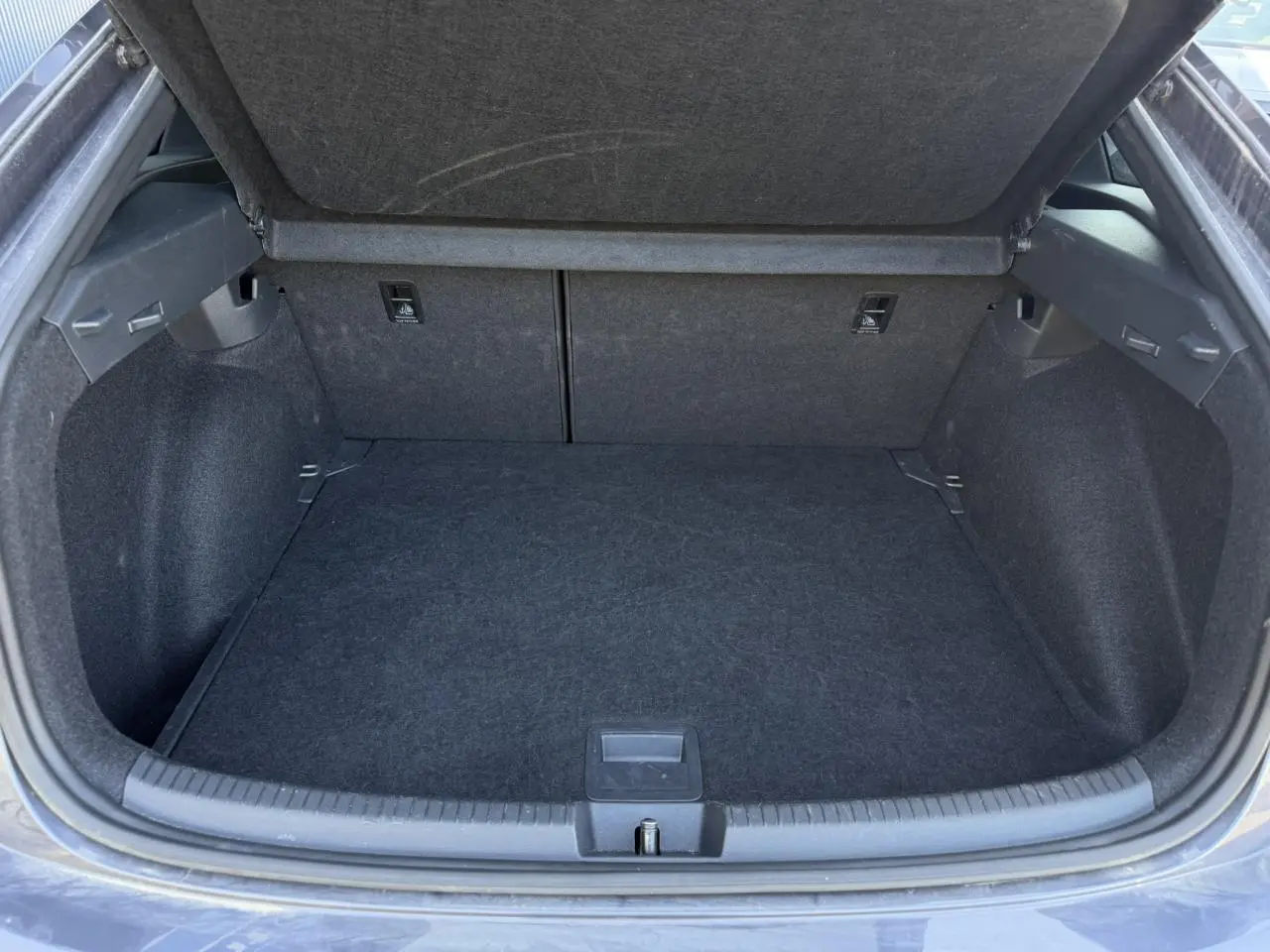 Coffre ouvert vu de face du Volkswagen Taigo gris intense, montrant un espace de chargement propre et spacieux.