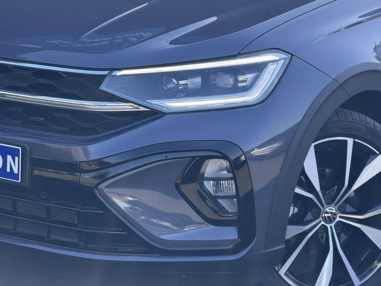 Gros plan sur l'avant droit du Volkswagen Taigo gris intense, mettant en valeur le phare Matrix LED et la jante alliage 18 pouces.