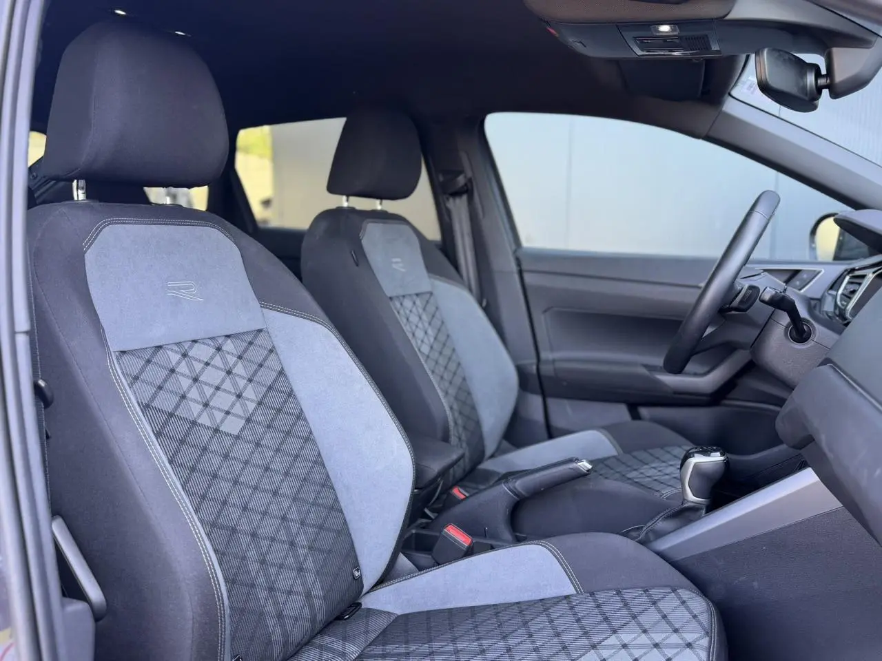 Vue intérieure côté gauche du Volkswagen Taigo R-Line 2025, sièges sport bi-matière gris avec logo R brodé.