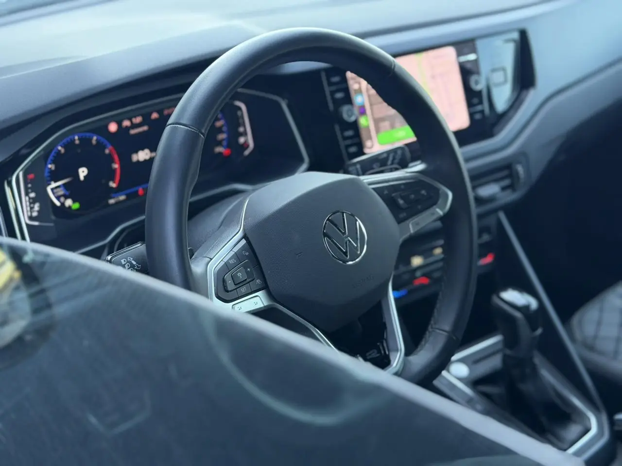 Vue intérieure centrée sur le volant multifonctions cuir Volkswagen, avec tableau de bord numérique et écran tactile visible.