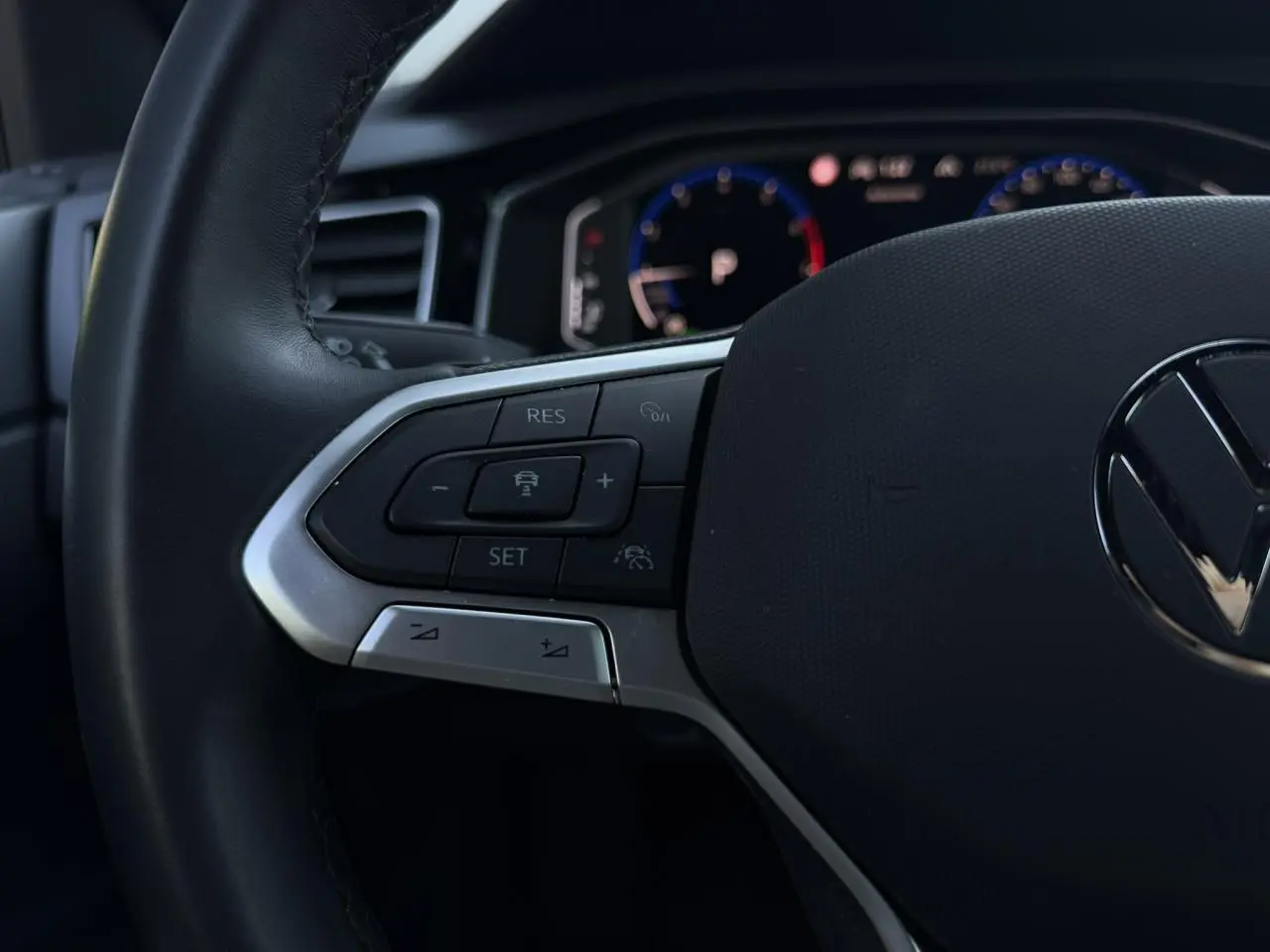 Gros plan sur le volant multifonctions cuir noir du Volkswagen Taigo 2025 avec commandes de régulateur adaptatif.