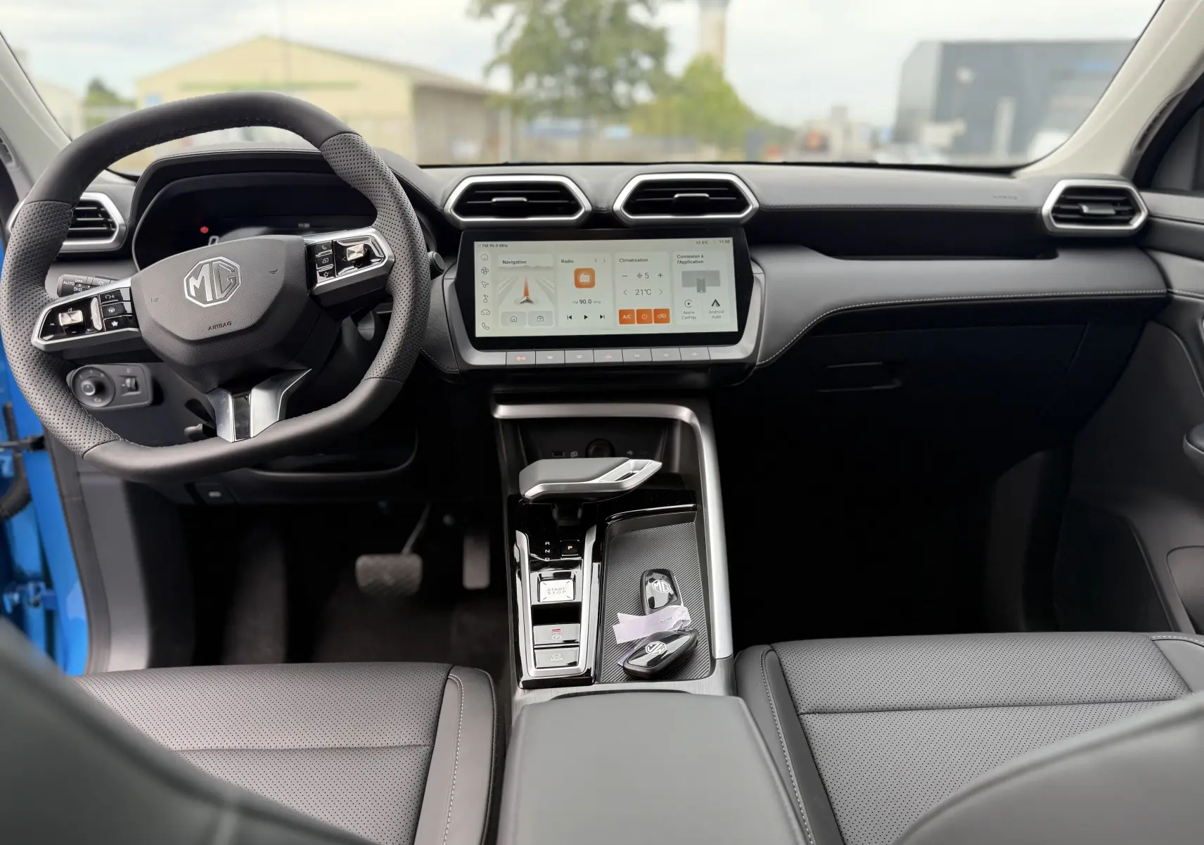 Vue intérieure avant du MG ZS 1.5L Hybrid+ 2025, montrant le tableau de bord noir avec écran tactile et volant multifonction.